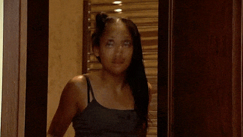 a woman is standing in front of a mirror in a bathroom brushing her hair .