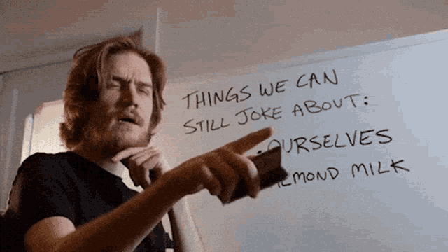 a man is pointing at a white board that says things we can still joke about
