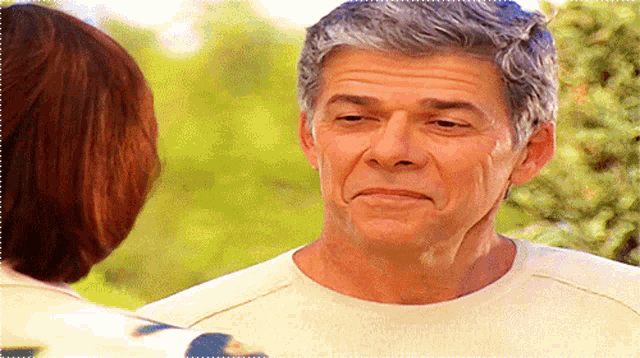 a man with gray hair and a white shirt looks at a woman