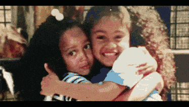 two little girls are hugging each other and one of them is wearing a shirt that says ' i love you ' on it