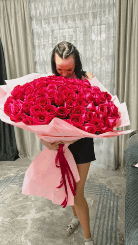 a woman holds a large bouquet of red roses