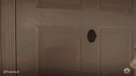 a man in a suit is standing in a doorway looking at a woman .