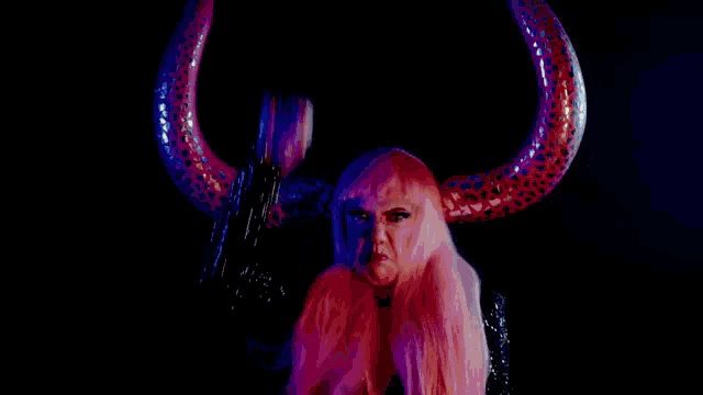 a woman with pink hair is wearing a bull horn