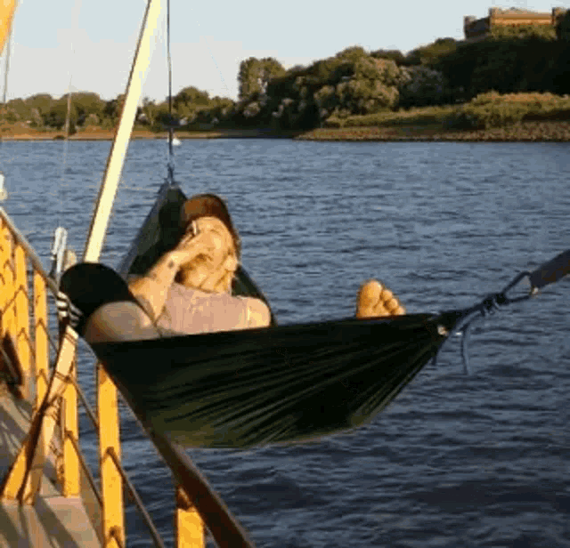 a man laying in a hammock on a boat