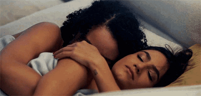 a man and a woman are hugging each other while laying in bed .