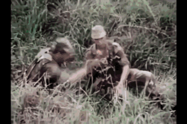 a group of soldiers are sitting in the grass talking .