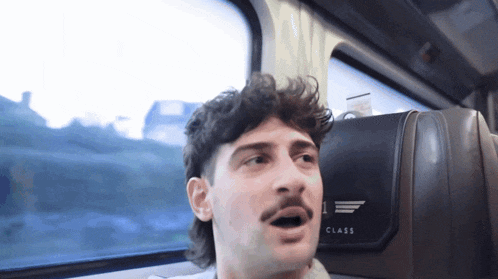 a man is sitting in a class seat on a bus