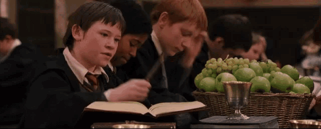 a group of young boys are sitting at a table reading books