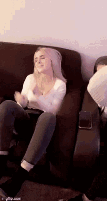 a woman is sitting on a couch with her eyes closed and a cell phone on her lap .