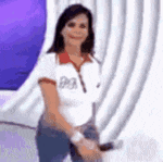 a woman is standing in front of a purple curtain and smiling .