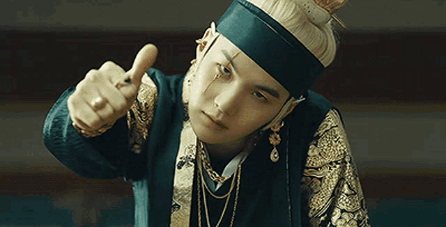 a young man in a traditional costume is giving a thumbs up .