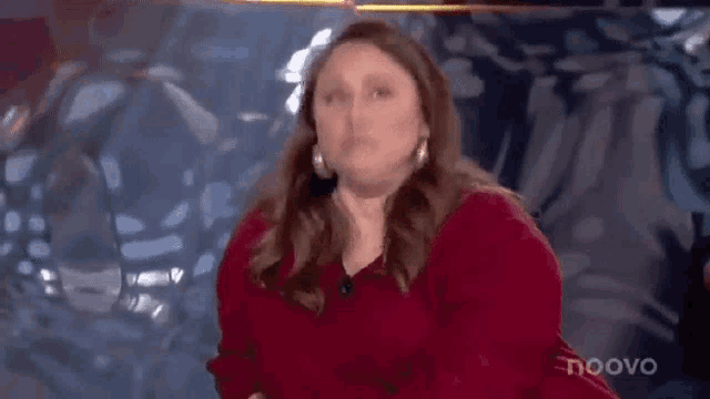 a woman in a red sweater is making a funny face .