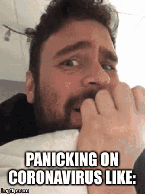 a man with a beard is biting his nails while laying in bed .