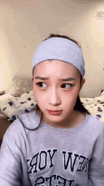 a woman wearing a headband and a grey sweater that says aoy wex