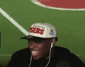 a man wearing a philadelphia tigers hat and earphones is smiling .