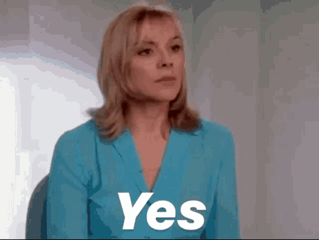 a woman in a blue suit is sitting in a chair with the word yes written on her chest .