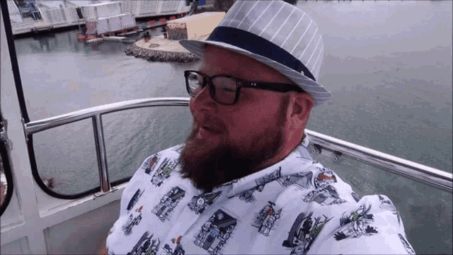 a man with a beard wearing a hat and glasses is sitting on a boat