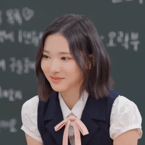 a girl wearing a white shirt and a blue vest with a pink bow