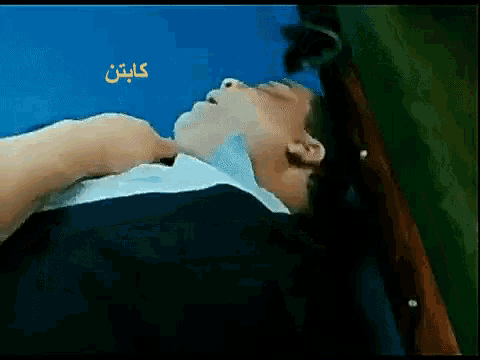 a man laying on a bed with a blue background and the word captain in yellow