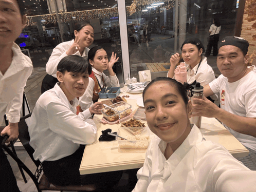 a group of people sitting around a table with a man wearing a t-shirt that says ' a ' on it