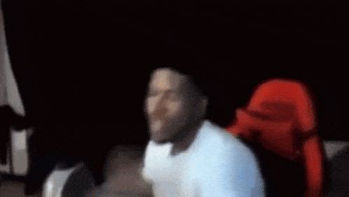 a blurry picture of a man in a white shirt with a red hat on his head .