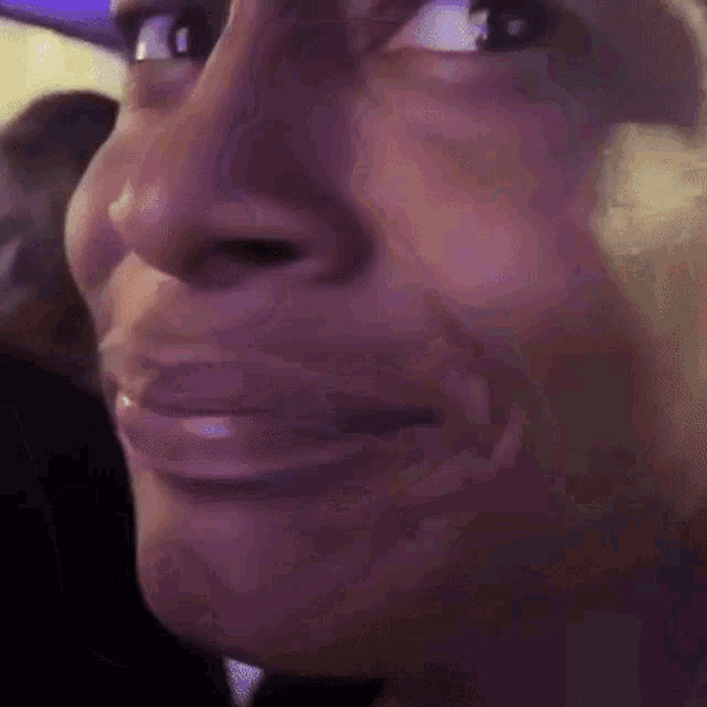 a close up of a person 's face with a purple background and a smile .