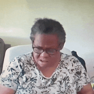 an older woman wearing glasses is sitting on a couch