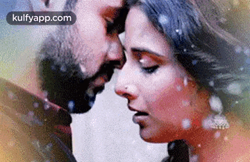 a man and a woman are touching their foreheads .