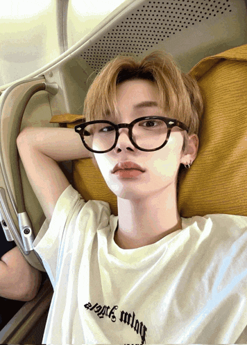 a young man wearing glasses and a white shirt that says angels wings