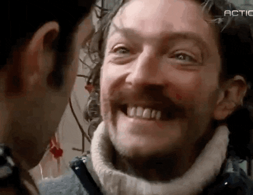 a man with a beard is smiling at another man .