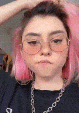 a girl with pink hair wearing glasses and a necklace