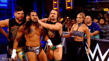 a group of wrestlers are standing next to each other in a wrestling ring
