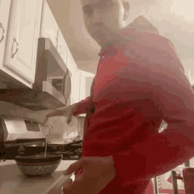 a man in a red shirt pouring liquid into a bowl