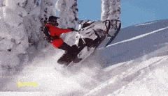 a man is riding a snowmobile down a snowy hill .