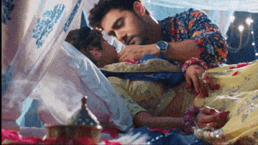 a man is putting his hand on a woman 's stomach while they are laying on a bed .