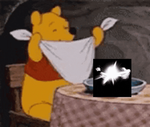 winnie the pooh is sitting at a table holding a towel over his face