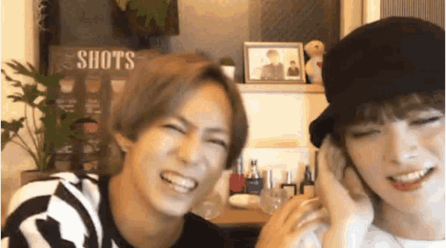 a man and a woman are sitting next to each other in a room and laughing .