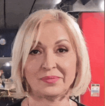 a close up of a woman 's face with a red wall behind her