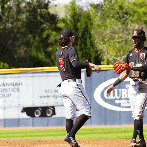 two baseball players on a field with an ad for vannah logistics group in the background