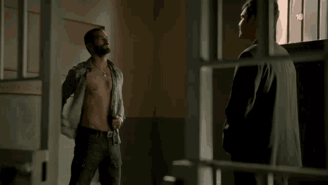 a shirtless man is standing in front of a window with the number 15 on the bottom