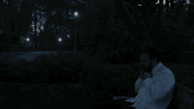 a man in a white shirt is sitting on a park bench