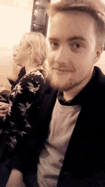a man with a beard is smiling in front of a woman in a floral shirt