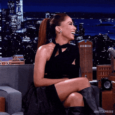a woman is sitting in a chair with her legs crossed and laughing