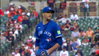 a baseball player wearing a blue jays jersey stands in front of a crowd