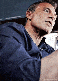 a man in a blue shirt is driving a car and looking up .