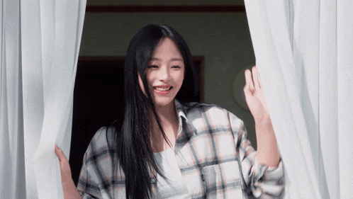 a woman in a plaid shirt is smiling while looking out a window