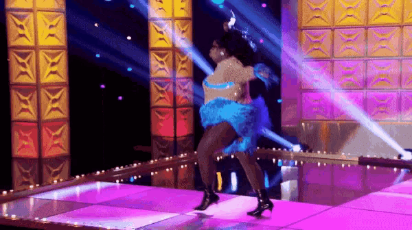a woman in a blue feathered dress is dancing on a dance floor