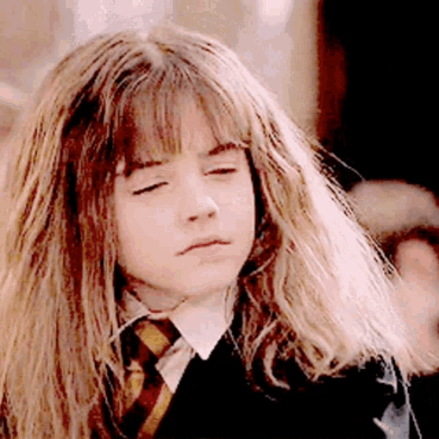 a close up of a young girl with her eyes closed wearing a tie .