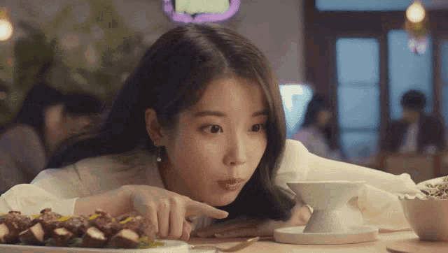 a woman sits at a table with a plate of food and a cup of coffee