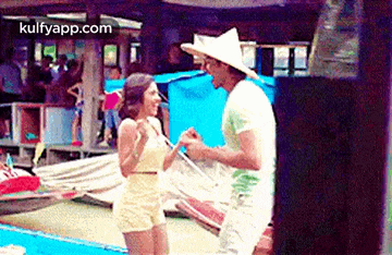 a man and a woman are standing next to each other on a beach holding hands .